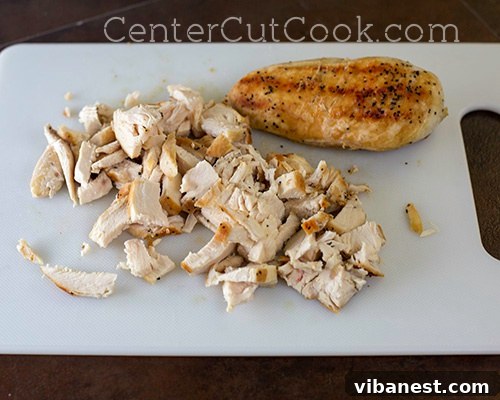 Chicken topping on flatbread Cooked grilled chicken breast pieces arranged on a cheesy pesto flatbread