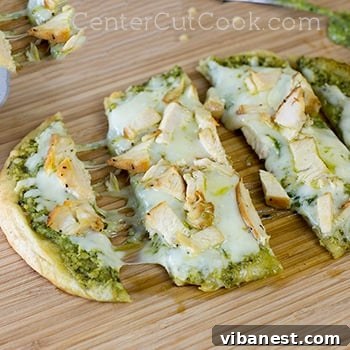 Close-up of a single slice of Chicken Pesto Flatbread showing melted cheese and toppings