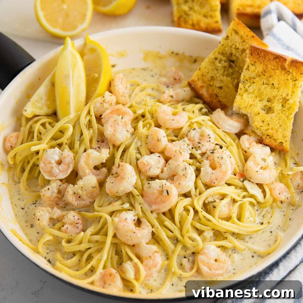 Lemon Garlic Shrimp Linguine 11 A wide shot of creamy shrimp scampi pasta in a large pan, glistening with garlic butter and dotted with juicy, pink shrimp, ready to be served.