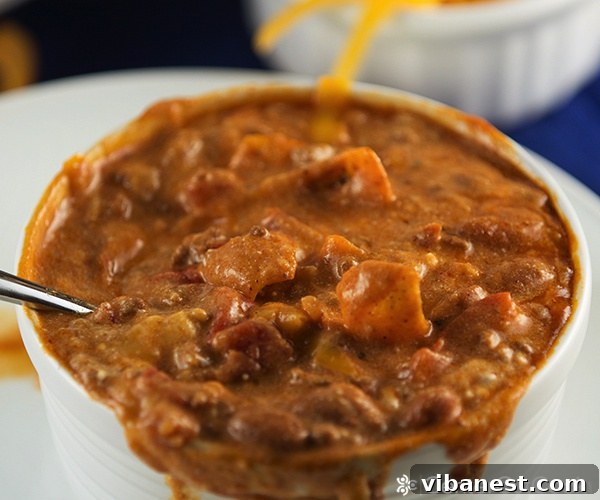 Slow cooker chili ready to be garnished. Slow cooker chili served in a rustic bowl with various toppings on the side.