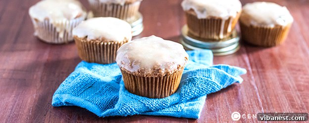 Delicious zucchini muffins with a generous drizzle of white chocolate peanut butter glaze, presented on a rustic wooden board.