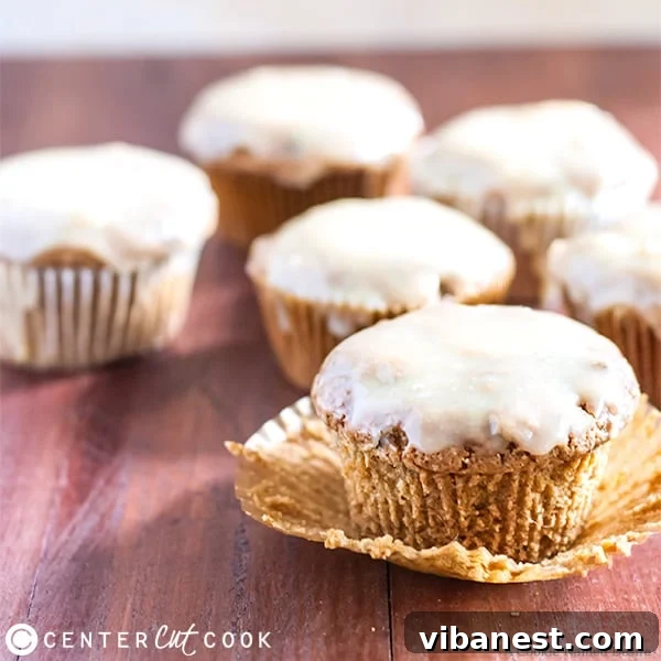 Zucchini Muffins with Peanut Butter Glaze Close-up A trio of freshly baked zucchini muffins, generously glistening with a smooth white chocolate peanut butter glaze, artfully arranged for serving.