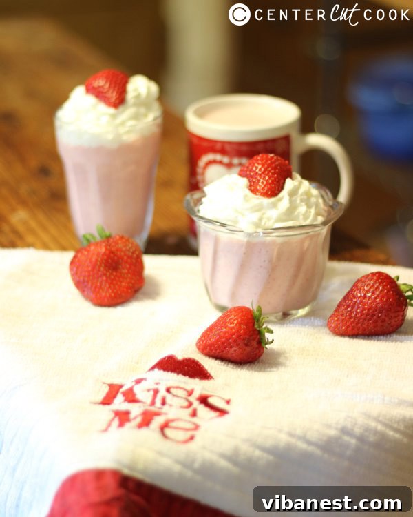Close-up of a refreshing strawberry shortcake smoothie in a glass, showing its creamy texture and pink hue.
