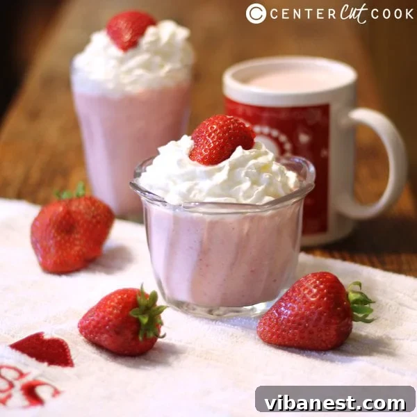 A vibrant strawberry shortcake smoothie presented in a glass, with fresh strawberries and a hint of whipped cream.