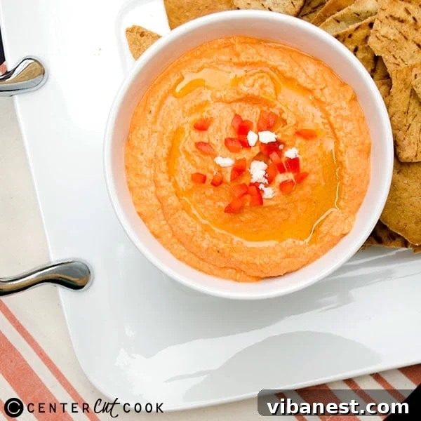 A bowl of finished Red Pepper Feta Dip with a spoon, ready to serve