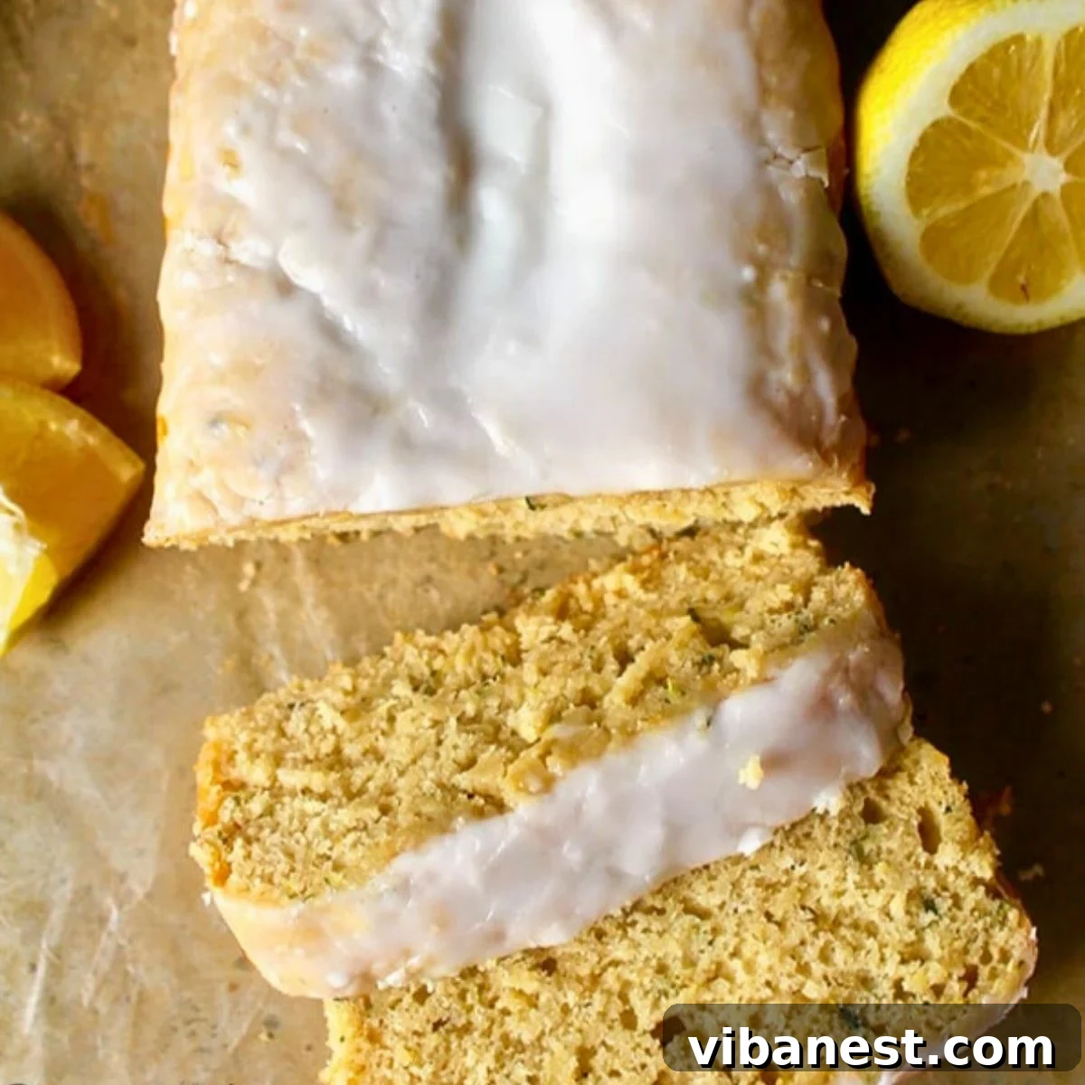 Bright Lemon Zucchini Loaf 2 A beautifully moist lemon zucchini bread with a glistening glaze drizzled generously on top, artfully sliced on a rustic cutting board, showcasing its tender crumb.