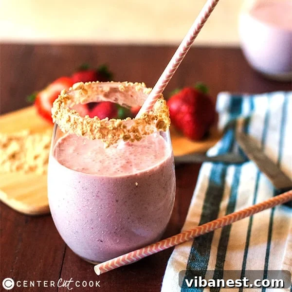 Final presentation of the Strawberry Cheesecake Smoothie with graham cracker rim and a straw, ready to be enjoyed