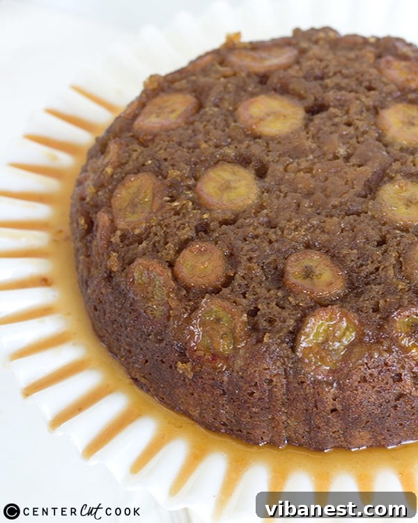The golden-brown banana upside down skillet cake, freshly inverted onto a white cake stand, showcasing its beautiful caramelized topping.