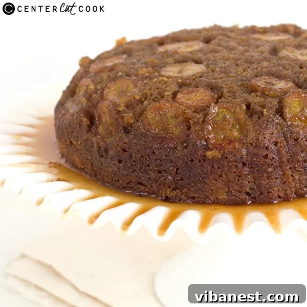A slice of banana upside down skillet cake served on a plate, revealing the moist cake texture and the rich banana caramel topping.