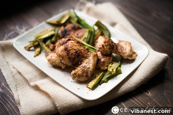 Close-up of roasted chicken thighs and vibrant green okra pods in a skillet, ready to be served.
