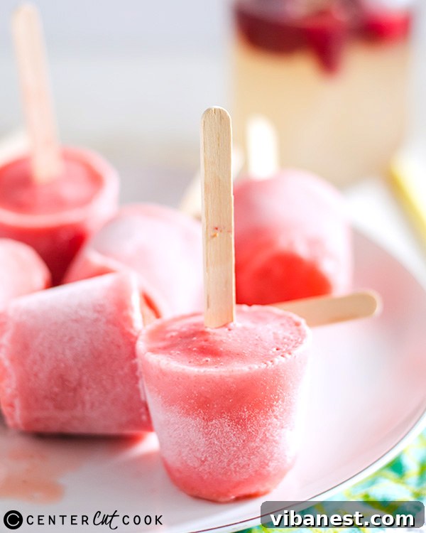 strawberry-lemonade-ice-pops-2.jpg Close-up of a perfectly frozen strawberry lemonade ice pop, showing its vibrant pink hue and a touch of condensation