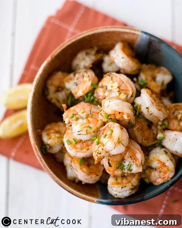 parmesan-roasted-shrimp-2.jpg A serving of garlic parmesan shrimp on a white plate with fresh lemon wedges and parsley.
