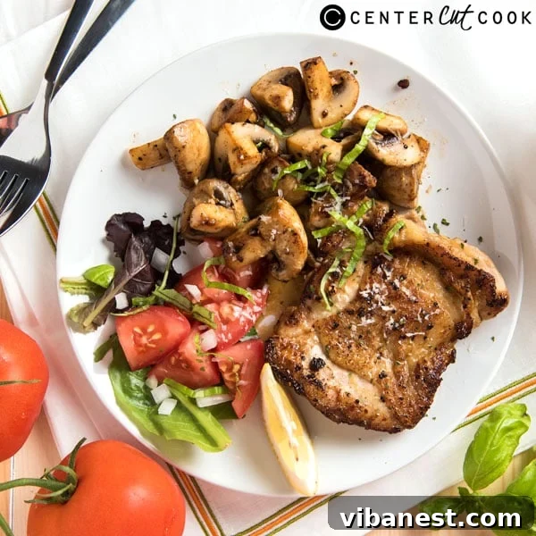 Plated Lemon Pepper Chicken with a side of greens, garnished with basil and parmesan