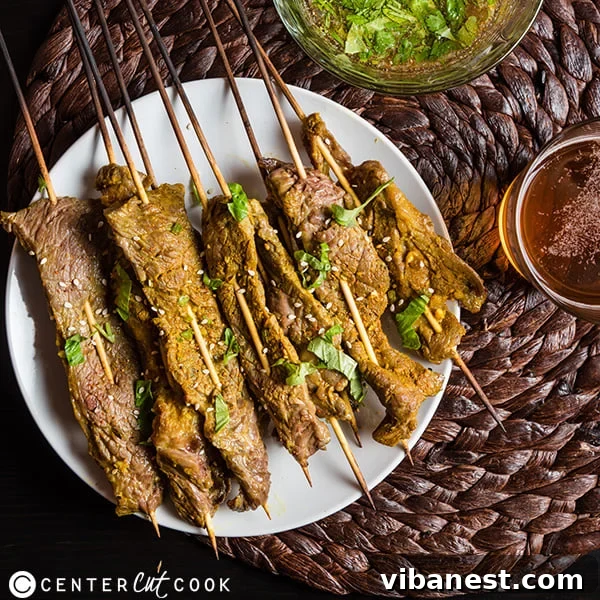 Plated Thai beef skewers with lime wedges and fresh herbs