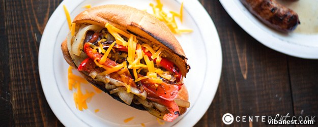 Ready-to-Eat Bratwurst Hot Dogs with Toppings Two perfectly prepared bratwurst hot dogs in toasted hoagie rolls, loaded with sautéed onions and peppers, ready to be enjoyed.