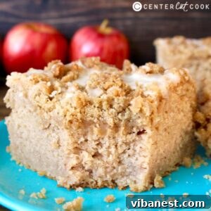 Warm Apple Cinnamon Swirl Coffee Cake 2 piece of apple cinnamon coffee cake on a plate. Fresh apples sitting in background.