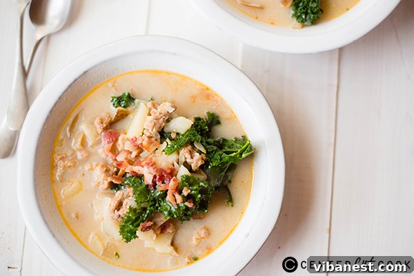 A close-up of Olive Garden Zuppa Toscana soup in a white bowl with a spoon