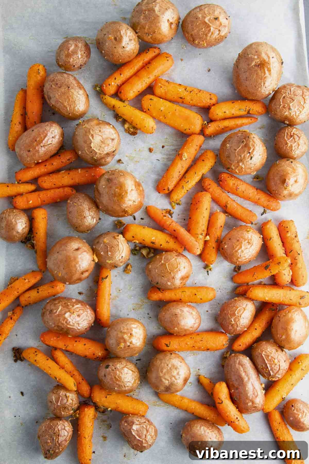 Golden Garlic Roasted Potatoes and Carrots 7 Golden-brown roasted baby carrots and potatoes on a sheet pan just after they come out of the oven, showing their crispy texture.