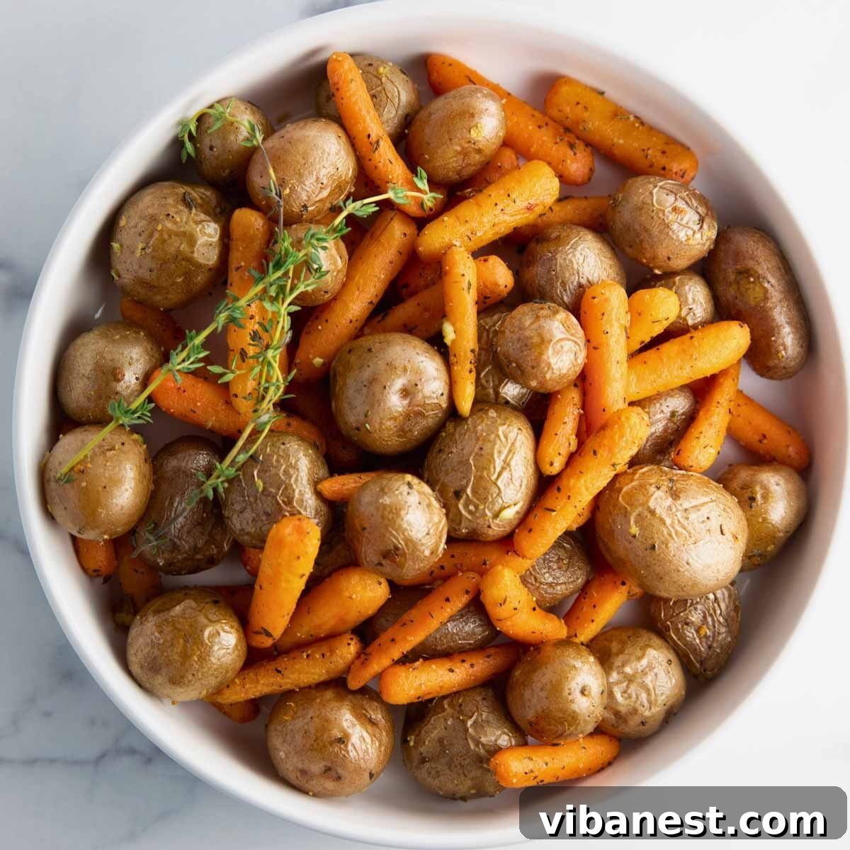 Golden Garlic Roasted Potatoes and Carrots 8 Close-up shot of roasted baby potatoes and carrots seasoned with garlic and thyme, ready to serve.