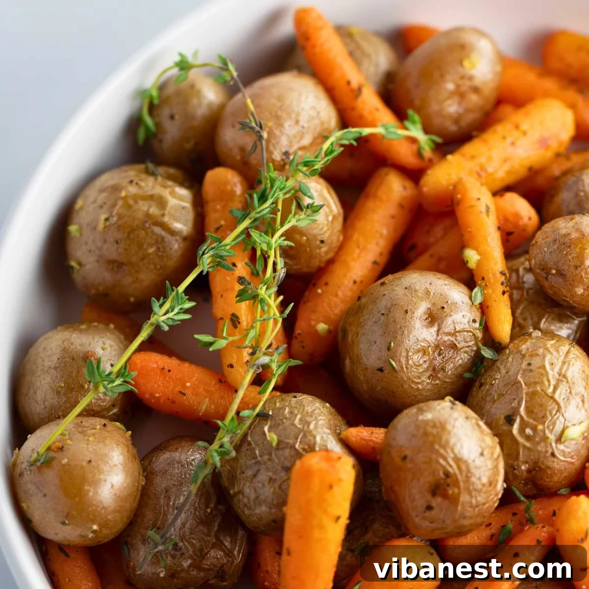 Golden Garlic Roasted Potatoes and Carrots 9 Close-up of golden-brown roasted baby potatoes and carrots in a serving bowl, showcasing their delicious texture and seasoning.