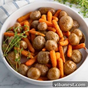 Golden Garlic Roasted Potatoes and Carrots 10 Close-up image of a bowl filled with garlic roasted baby potatoes and carrots, garnished with fresh thyme, ready to serve.