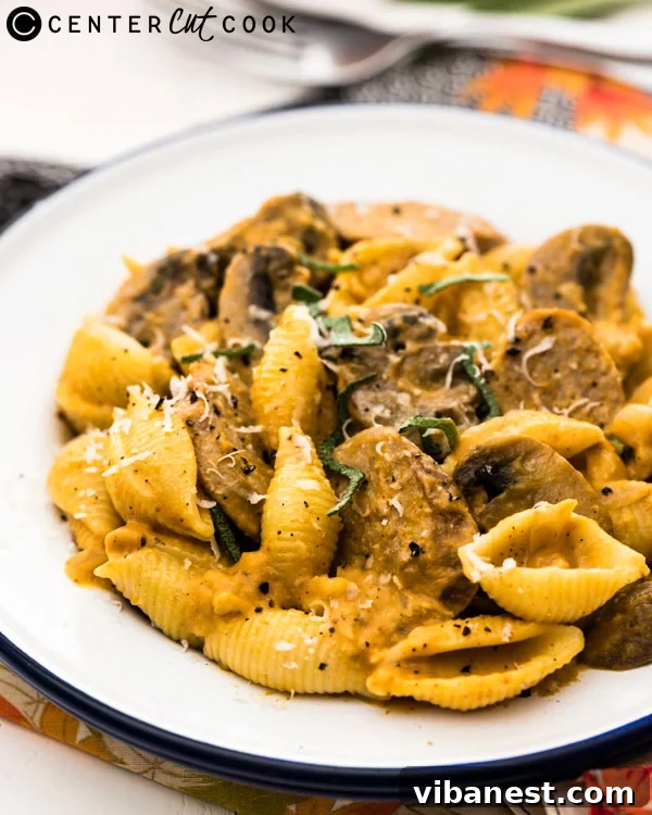 Perfectly Coated Pasta in a Rich Pumpkin Sauce Close-up of creamy pumpkin pasta with sausage, garnished with fresh sage