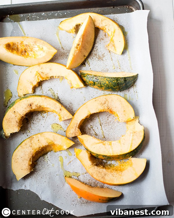 Seasoned Acorn Squash Slices on Baking Sheet Slices of roasted acorn squash seasoned with salt and pepper, arranged on a baking sheet