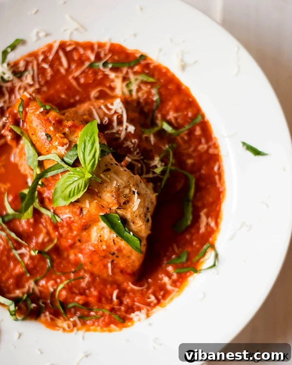 Slow Cooker Chicken Parmesan simmering Close-up of golden-brown chicken breasts simmering in a rich tomato sauce in a slow cooker