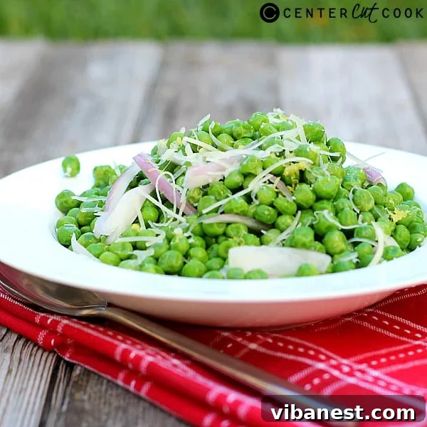 Bowl of freshly made Parmesan Peas with Shallots and Lemon, garnished with lemon zest