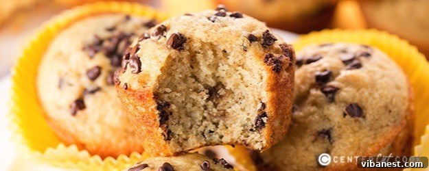 Golden brown banana muffins cooling on a wire rack, with fresh bananas in the background