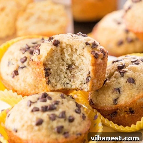 Plated banana muffins, one cut open to reveal its moist interior, with a glass of milk