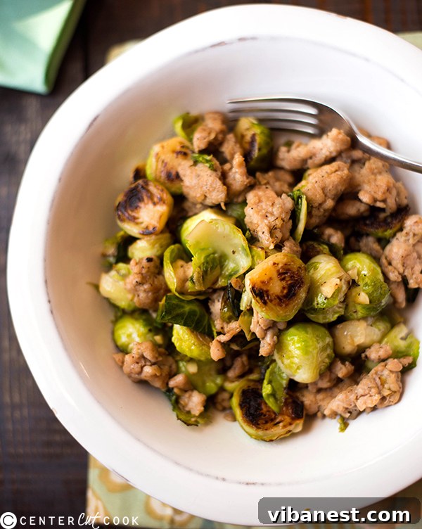 close up of roasted chicken italian sausage and brussels sprouts in a pan