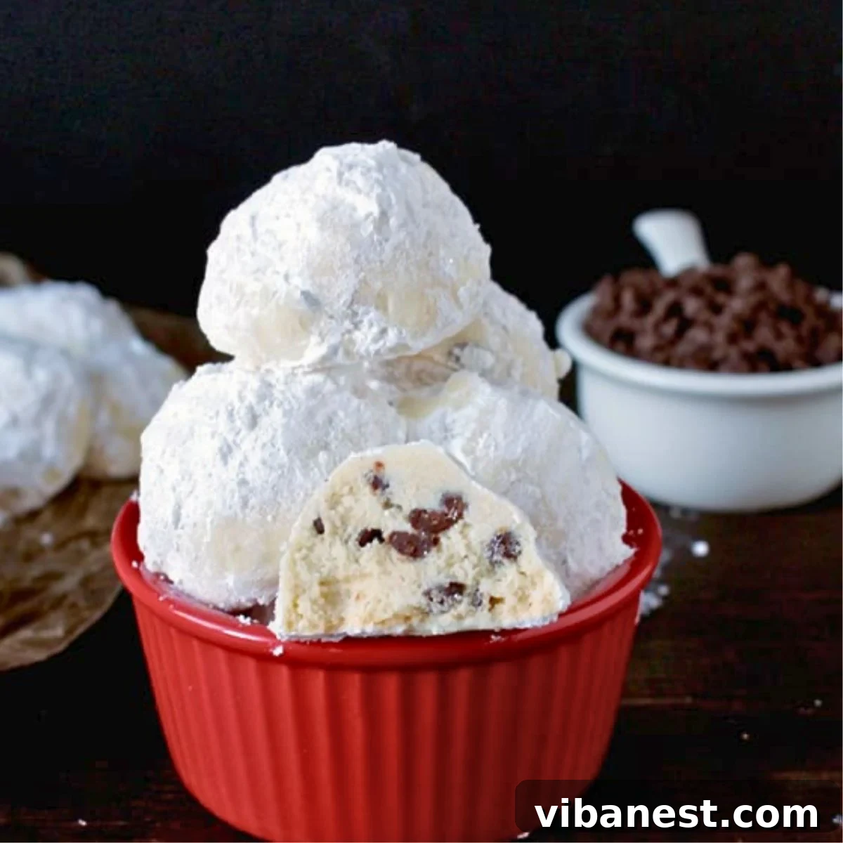 Snow-Kissed Chocolate Chip Delights 2 Delicious chocolate chip snowball cookies dusted with powdered sugar, ready for holiday celebrations.