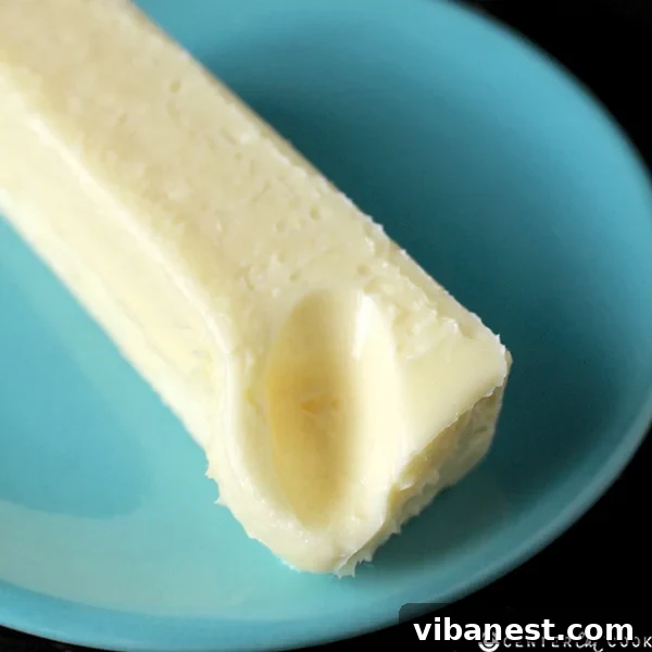 cookie_baking_tips_butter.jpg Softened sticks of butter, one unwrapped and one still in its wrapper, at room temperature on a wooden cutting board, ready for baking.
