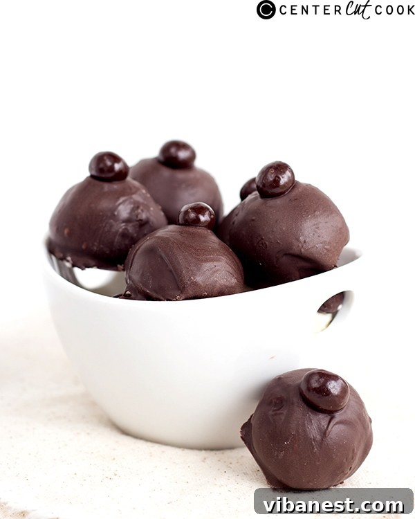 A close-up view of a finished Eggnog Latte Truffle, showcasing its rich dark chocolate coating and delicate espresso bean topping.