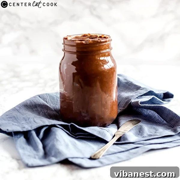 The finished homemade Nutella in a jar, ready to be enjoyed, with a small spoon next to it.