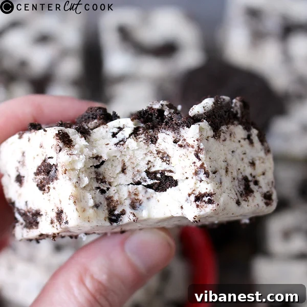 Decadent Oreo Cheesecake Fudge 3 A block of Oreo Cheesecake Fudge freshly poured into a foil-lined baking pan, topped with extra crushed Oreos