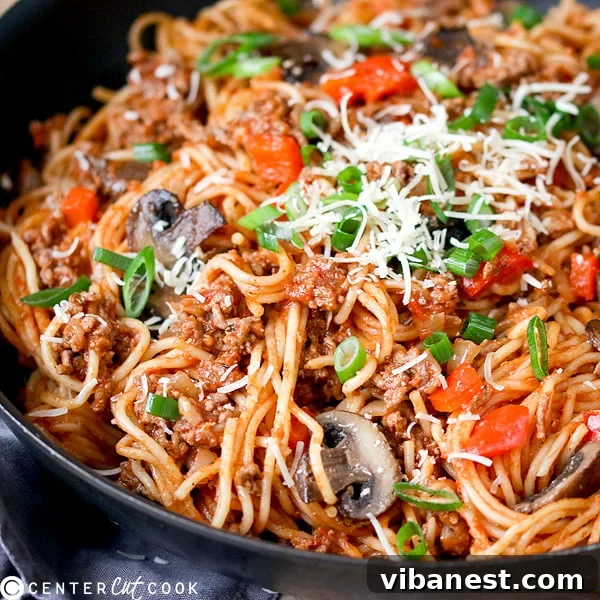 Close-up of One-Pot Pasta Bolognese ready to serve, garnished with parmesan and scallions
