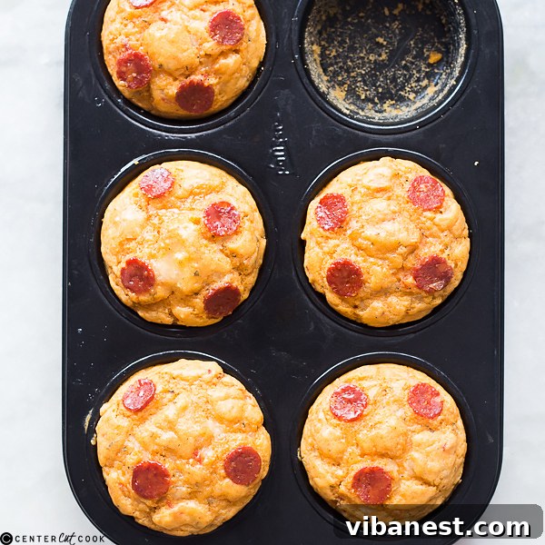 pepperoni-cheese-pizza-muffins-3.jpg A cluster of golden-brown pepperoni cheese pizza muffins on a cooling rack, ready to be served