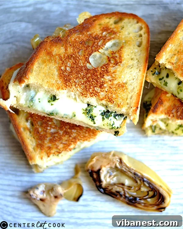 Close-up of a Pesto Artichoke Grilled Cheese cut in half, showing melted cheese and fillings