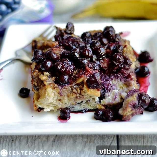 Close-up of Overnight Blueberry Banana French Toast being drizzled with homemade blueberry sauce