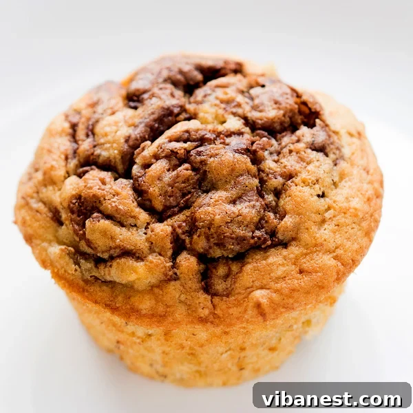 Close-up of raw Nutella Swirled Banana Muffin batter in a tin before baking, showing the distinct Nutella swirls.