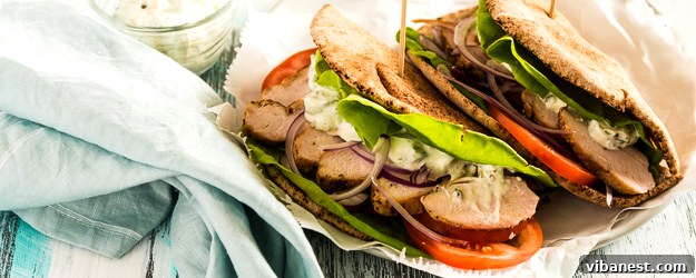 Delicious Slow Cooker Chicken Gyros served on warm pita bread with fresh tomatoes, lettuce, red onion, and a generous drizzle of homemade tzatziki sauce