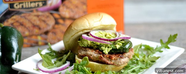 Delicious grilled sausage burgers with melted cheese, bacon, and grilled poblano peppers on buns, ready to be served for a summer cookout.