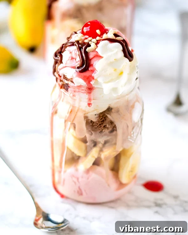 Perfectly Layered Mason Jar Banana Split Close-up of a beautifully layered Mason Jar Banana Split, showcasing the various ice cream flavors, banana slices, and whipped cream