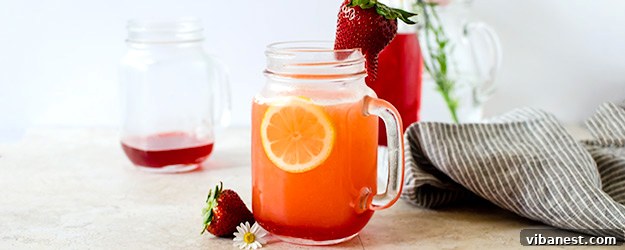 Vibrant homemade strawberry lemonade in a tall glass with fresh strawberry and lemon slices, perfect for summer