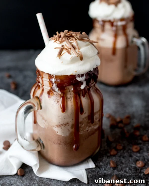 Delicious Frozen Hot Chocolate with Toppings Two glasses of frozen hot chocolate with whipped cream and chocolate shavings on a wooden board.