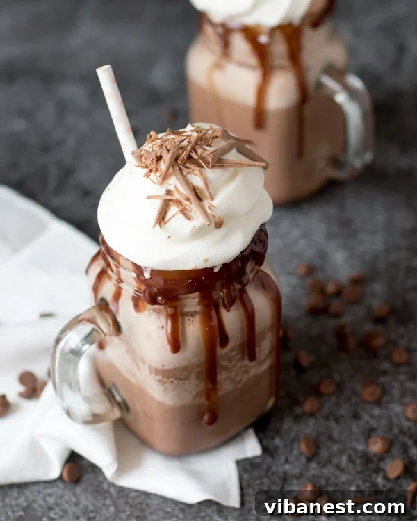 Enjoying Homemade Frozen Hot Chocolate A hand holding a glass of frozen hot chocolate topped with whipped cream and chocolate shavings.