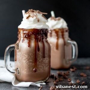 Frosty Cocoa Dream 2 Two mugs of frozen hot chocolate with abundant whipped cream and chocolate sauce.