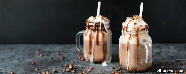 Overhead View of Finished Frozen Hot Chocolates Overhead shot of two glasses of frozen hot chocolate with whipped cream and chocolate curls on a light background.